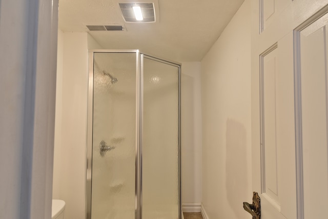 full bathroom with toilet, a shower stall, and visible vents