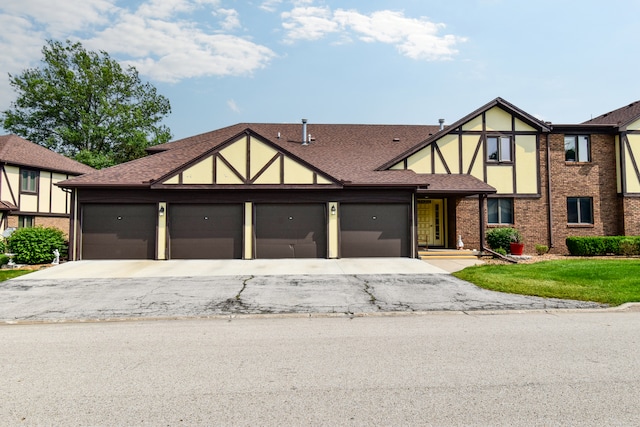 208 Carol Ct Unit A2, Pontiac, IL 61764 - tudor-style house featuring an attached garage, asphalt driveway, roof with shingles, and brick siding