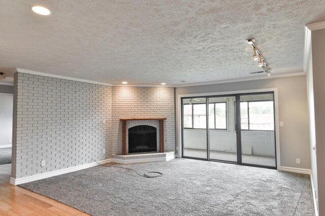 208 Carol Ct Unit A2, Pontiac, IL 61764 - unfurnished living room with a textured ceiling, baseboards, a brick fireplace, crown molding, and brick wall