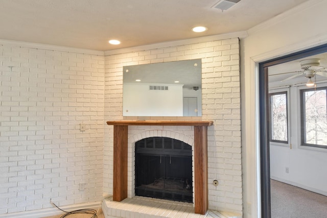 interior space with ceiling fan, a brick fireplace, visible vents, and crown molding