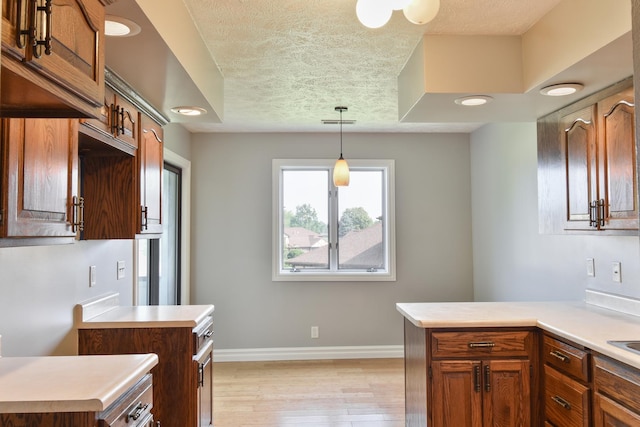208 Carol Ct Unit A2, Pontiac, IL 61764 - kitchen featuring light countertops, light wood-style flooring, hanging light fixtures, baseboards, and a textured ceiling