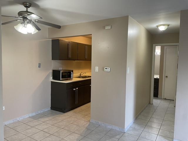 kitchen featuring light countertops, stainless steel microwave, a sink, and dark brown cabinets