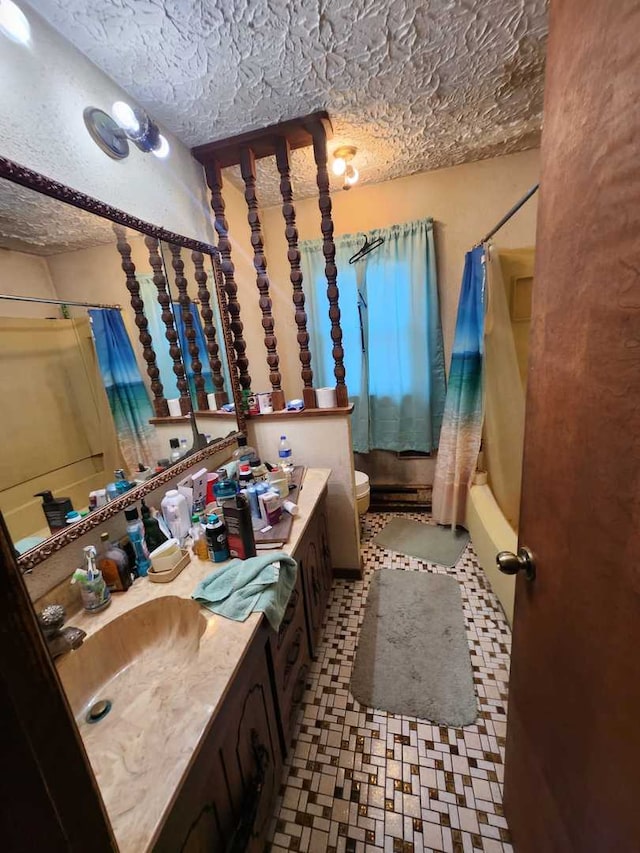 bathroom with toilet, shower / bath combo with shower curtain, a textured ceiling, and vanity