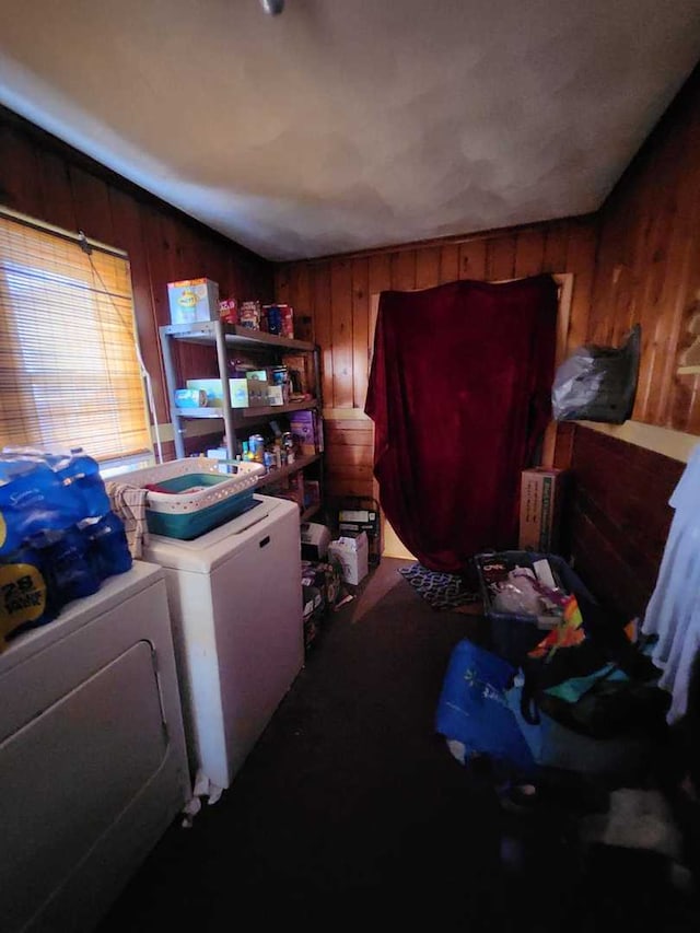 interior space with laundry area, washing machine and clothes dryer, and wood walls