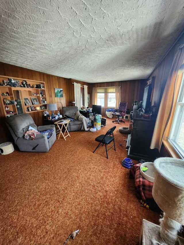 living area with a textured ceiling, carpet floors, and wooden walls