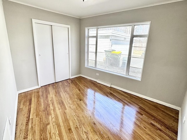 unfurnished bedroom with baseboards, a closet, visible vents, and wood finished floors