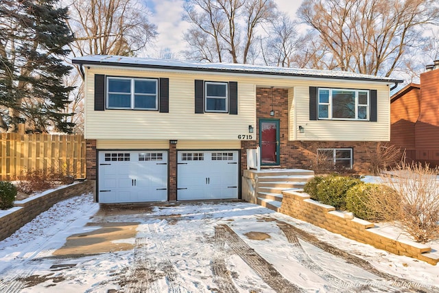 bi-level home featuring solar panels, brick siding, an attached garage, and fence