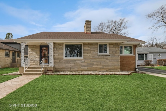 view of front of home with stone siding, roof with shingles, a chimney, and a front lawn