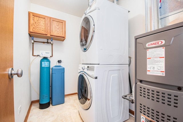 laundry room with laundry area, baseboards, stacked washing maching and dryer, and light tile patterned floors