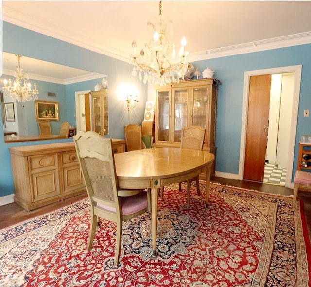 dining room with a chandelier, crown molding, baseboards, and wood finished floors