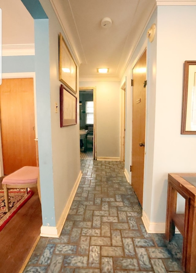 hall featuring brick floor, baseboards, and crown molding