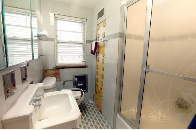 bathroom with toilet, a stall shower, and a sink