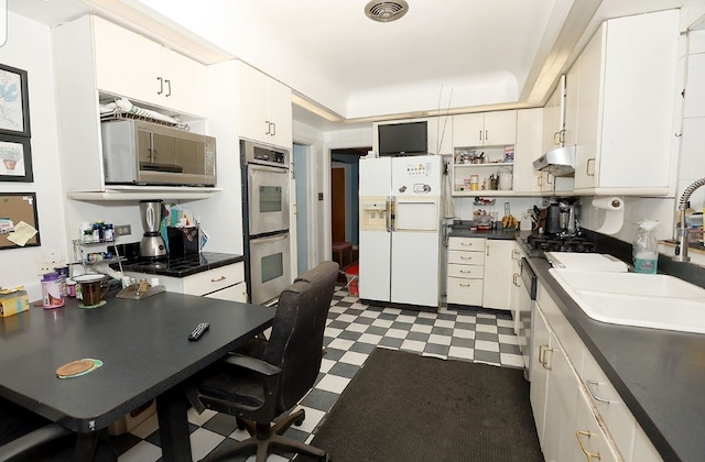 kitchen featuring dark countertops, visible vents, dark floors, stainless steel appliances, and a sink