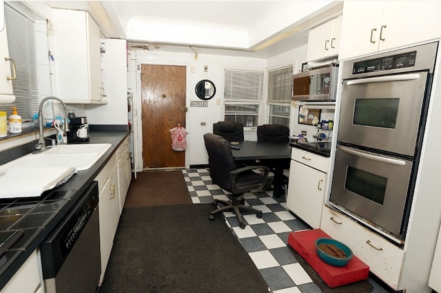 kitchen with white cabinets, dark floors, appliances with stainless steel finishes, and a sink