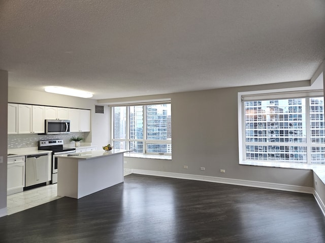 kitchen with white cabinets, a kitchen island, appliances with stainless steel finishes, light countertops, and a city view