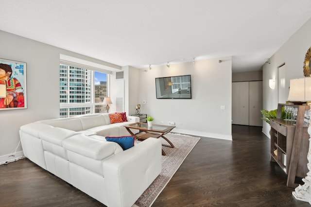 living room featuring dark wood-style flooring, rail lighting, visible vents, and baseboards