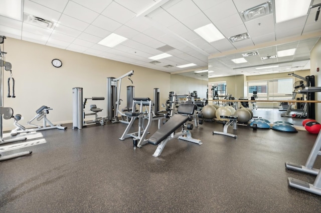 exercise room with visible vents, a drop ceiling, and baseboards