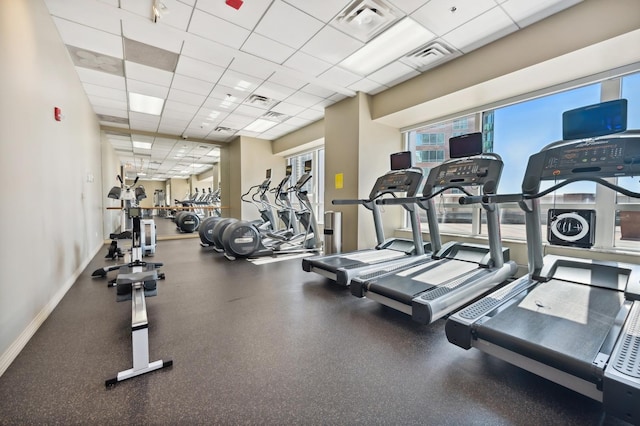 gym with a drop ceiling, visible vents, and baseboards