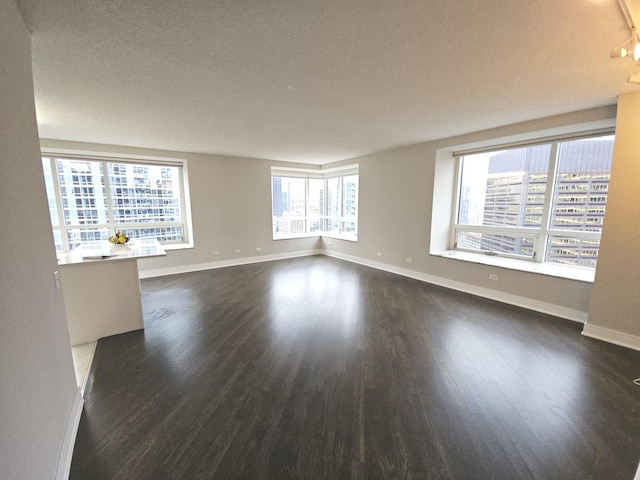 unfurnished room with baseboards, dark wood-type flooring, and a city view