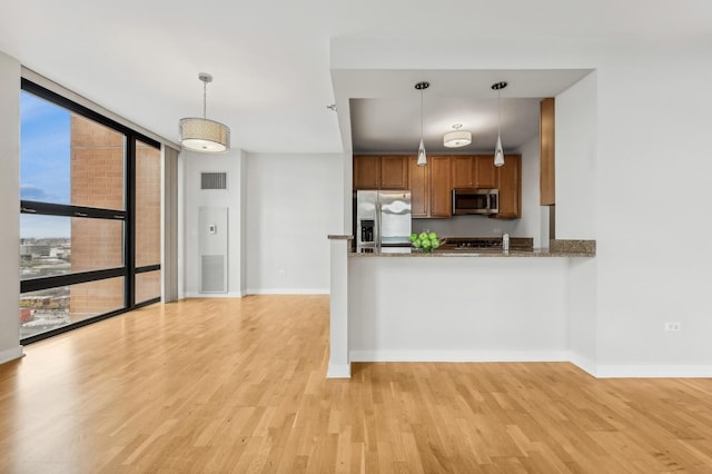 kitchen featuring appliances with stainless steel finishes, pendant lighting, brown cabinets, and visible vents