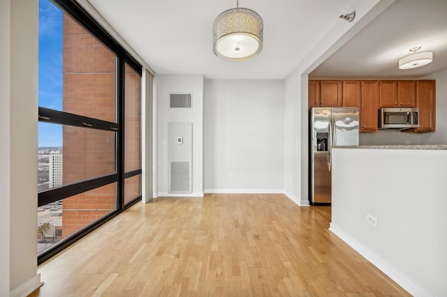 interior space featuring brown cabinets, stainless steel appliances, light countertops, visible vents, and expansive windows