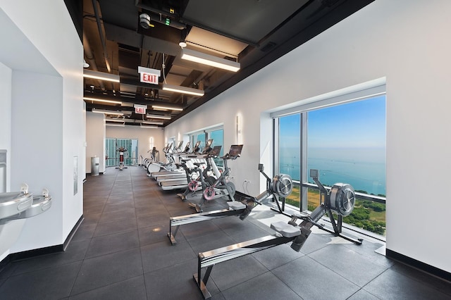 workout area featuring a water view and baseboards