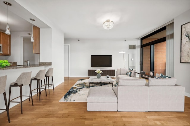 living room with light wood finished floors, visible vents, and baseboards