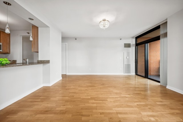 interior space with light wood-style floors, visible vents, expansive windows, and baseboards