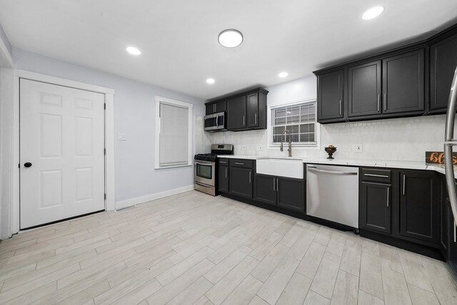 3323 N Central Park Ave, Chicago, IL 60618 - kitchen featuring light wood-style flooring, baseboards, dark cabinets, a sink, and stainless steel appliances