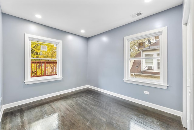 unfurnished room featuring a healthy amount of sunlight, baseboards, visible vents, and wood finished floors