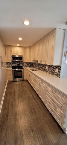 kitchen featuring decorative backsplash, dark wood finished floors, appliances with stainless steel finishes, light countertops, and a sink