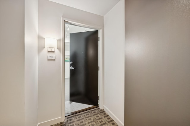 corridor featuring tile patterned floors and baseboards