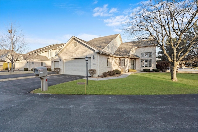 view of front of property featuring a shingled roof, aphalt driveway, an attached garage, a front lawn, and brick siding