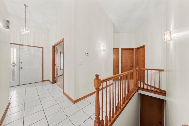 entryway featuring a notable chandelier, a towering ceiling, baseboards, and light tile patterned floors