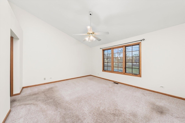 carpeted spare room with lofted ceiling, ceiling fan, visible vents, and baseboards