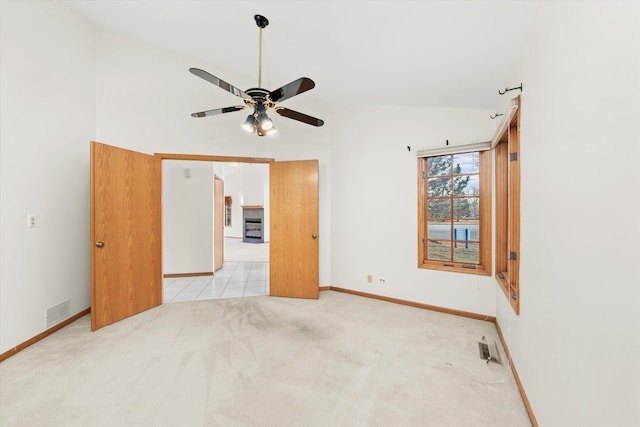 unfurnished room with a ceiling fan, light colored carpet, visible vents, and baseboards