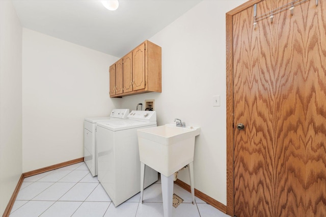 laundry area featuring washing machine and dryer, cabinet space, baseboards, and light tile patterned floors