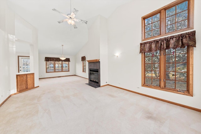 living area featuring a fireplace, light colored carpet, ceiling fan, high vaulted ceiling, and baseboards