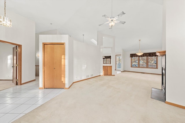 unfurnished living room featuring light tile patterned floors, light carpet, high vaulted ceiling, baseboards, and ceiling fan with notable chandelier