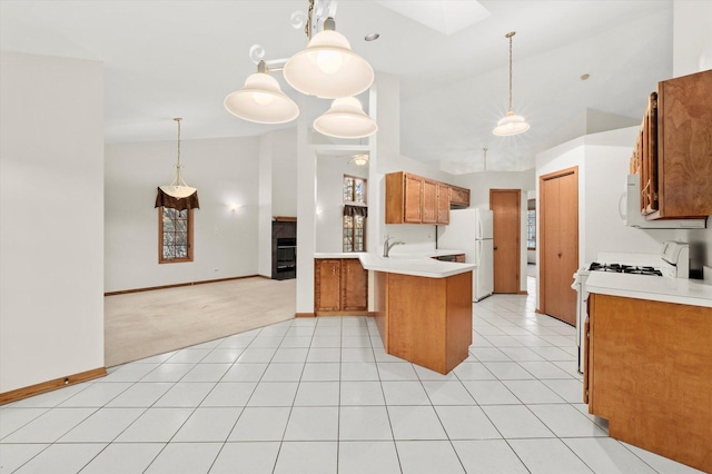 kitchen with white appliances, a skylight, brown cabinetry, a peninsula, and light countertops