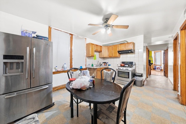 kitchen with light countertops, decorative backsplash, appliances with stainless steel finishes, a sink, and under cabinet range hood