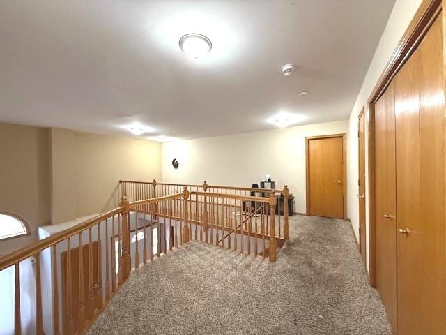 hallway with carpet floors and an upstairs landing