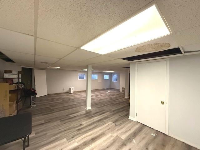 basement featuring a paneled ceiling and wood finished floors