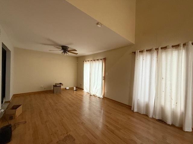 empty room featuring ceiling fan, light wood-style flooring, and baseboards