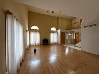 unfurnished living room featuring stairs, high vaulted ceiling, wood finished floors, and visible vents