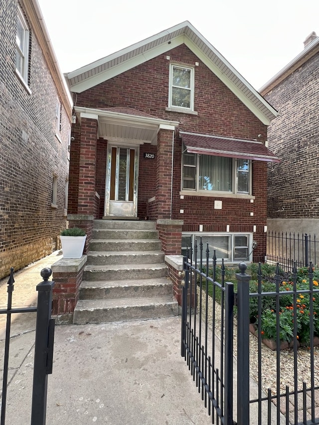 view of front of house with a fenced front yard, a gate, and brick siding