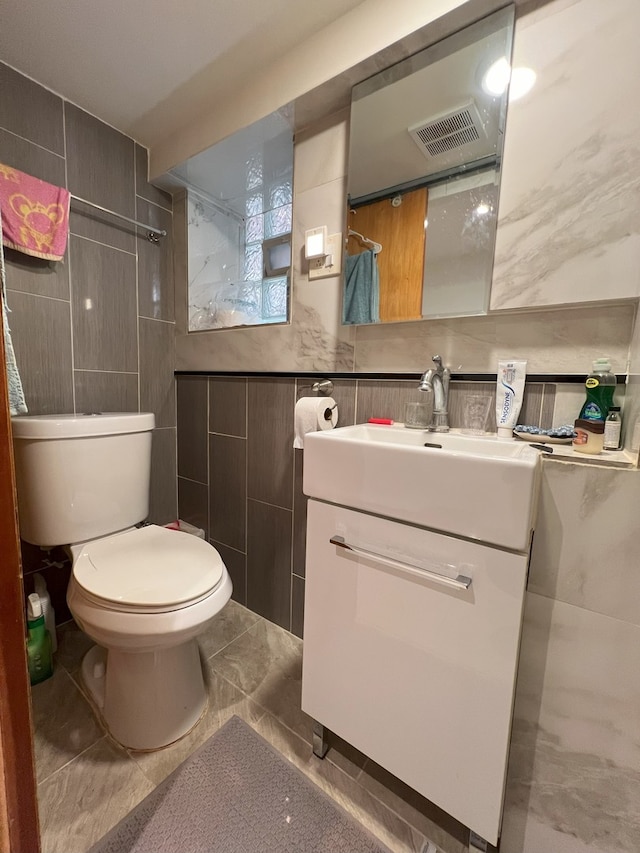 bathroom featuring toilet, visible vents, vanity, tile walls, and marble finish floor