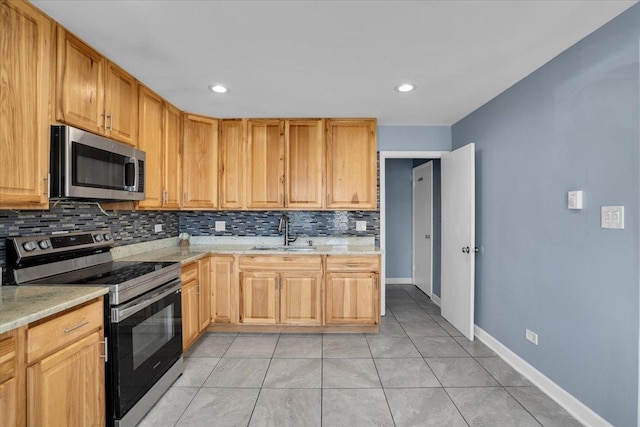 kitchen with stainless steel appliances, a sink, backsplash, and light stone countertops