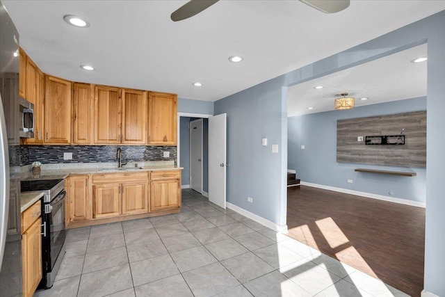 kitchen with light tile patterned floors, a sink, open floor plan, appliances with stainless steel finishes, and tasteful backsplash