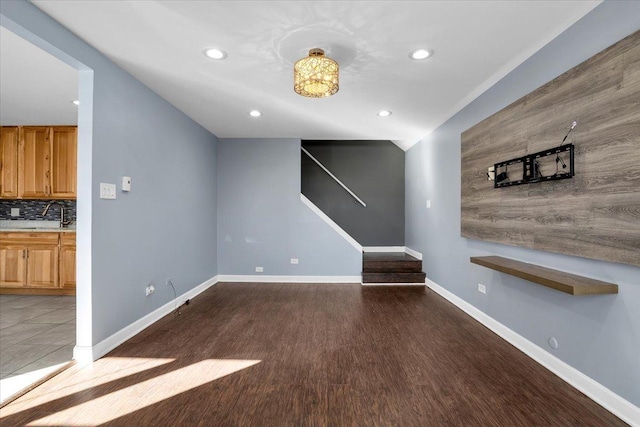 unfurnished living room with recessed lighting, a sink, dark wood finished floors, and baseboards